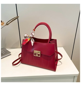 Detail of red leather trapezoid handbag with decorative silk scarf and gold metal lock