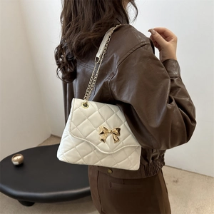 Chic white quilted crossbody bag with a golden bow clasp and chain strap for women