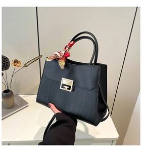 Close-up of black textured handbag with G-buckle detail and floral scarf on handle