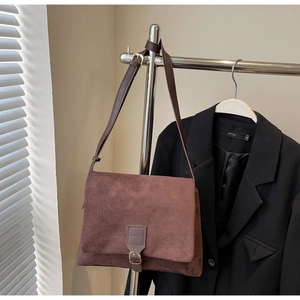 Detail of vintage brown suede shoulder bag showing adjustable strap and matte leather texture