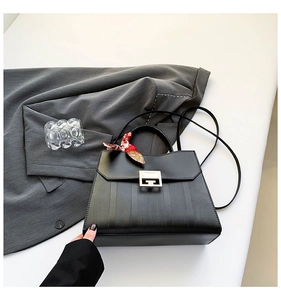 Detail of black vertical striped tote with golden geometric lock and silk scarf accent