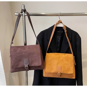 Detail view of large matte suede shoulder bags in dark brown and ginger yellow colors