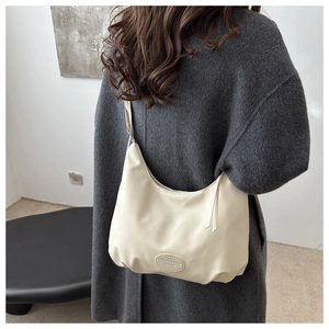 Detail showing the oval fashion label on the bottom of a beige minimalist hobo tote bag