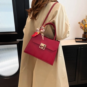 Red crossbody bag with silk scarf handle and metal lock shown on shoulder