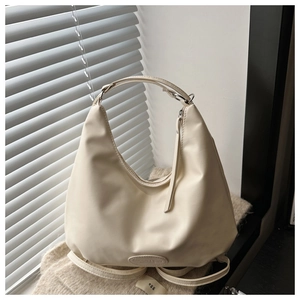Detail view of cream leather crescent tote bag on soft knit fabric with shadow detail