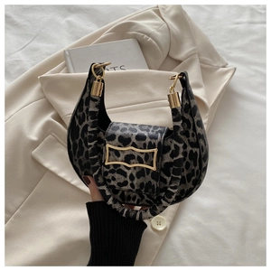 Detail of leopard print crescent bag with gold buckle resting on a stylish blazer