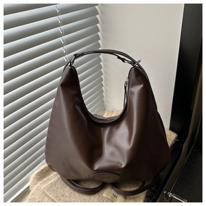 Detail of dark brown leather hobo bag with wide strap and oval tag on knit fabric