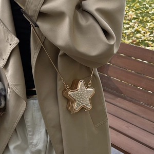 Sac de soirée en forme d'étoile avec strass et chaîne dorée porté par un mannequin