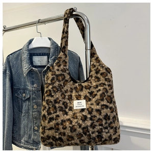 Close-up of leopard print faux shearling tote bag hanging on a rack with high quality tag