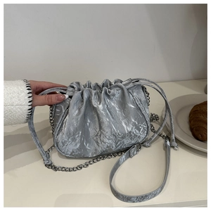 Detail of silver pleated bucket bag with metallic texture and thin chain strap