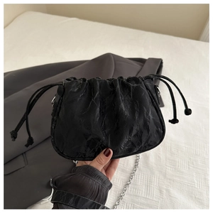 Detail of black pleated cloud bag with drawstring and silver metal chain strap