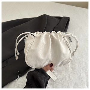 Detail of white pleated drawstring bag with marble texture and metal chain strap