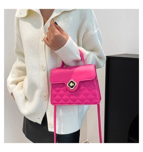 Detail of pink crossbody bag featuring quilted texture and clover twist lock closure