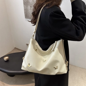 Borsa tote retrò color crema con farfalle dorate a rilievo su un modello in giacca nera