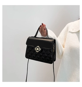 Detail of black crossbody bag with gold floral clasp and diamond quilt pattern