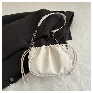 Detail of white pleated cloud bag with silver chain strap on a black blazer