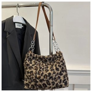 Detail of leopard print plush tote bag featuring leather strap and metal chain links