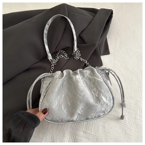 Detail of silver pleated dumpling bag featuring metallic texture and chain strap