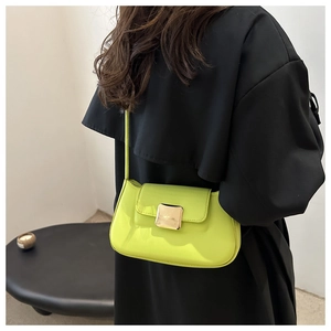 Dettaglio della borsa a spalla in pelle verniciata verde neon con fibbia dorata
