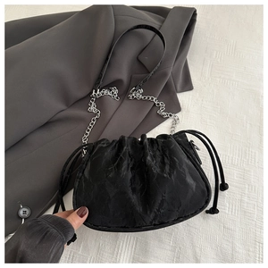 Detail view of black pleated drawstring bag with silver chain and textured fabric finish