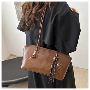 Detail of retro brown faux leather tote bag with thin straps and metal mesh pendant
