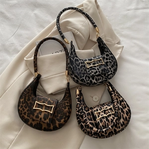 Three leopard print half-moon hobo bags with gold hardware on aesthetic background