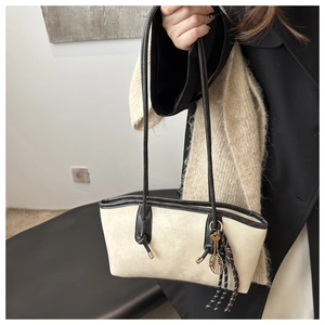 Detail of beige suede tote bag with brown straps and tennis racket metal charm