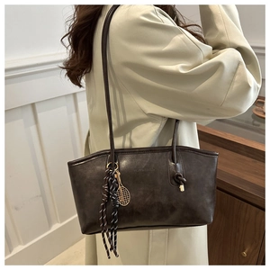 Detail of dark brown leather tote bag with vintage texture and tennis racket charm