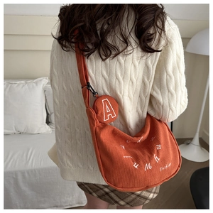 Dettaglio borsa tote in velluto a coste arancione con ricamo e pochette rotonda