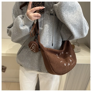Detailed texture of brown corduroy crescent bag with round 'A' letter coin purse pendant