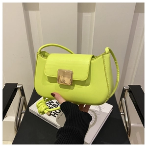 Dettaglio della borsa a tracolla in pelle verde neon con fibbia dorata e tracolla con nodi