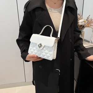 White quilted PU leather crossbody bag with flower clasp on elegant black trench coat