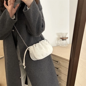 White pleated cloud shoulder bag with silver chain strap worn with a grey winter coat