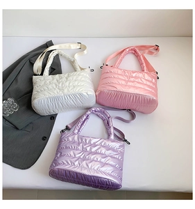 Flat lay of quilted down puffer bags in white, pink, and purple with metallic finish