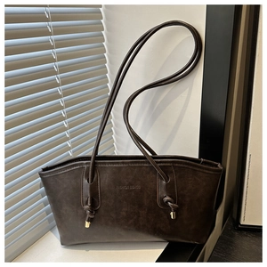 Detailed close-up of dark brown PU leather tote bag showing stylish knotted strap and metal tip