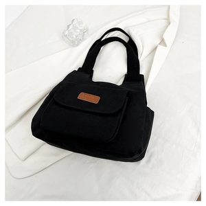 Dettaglio della borsa tote in nylon nero con tasca frontale e toppa in pelle marrone