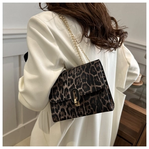 Detail view of leopard print crossbody bag with gold chain strap on white blazer