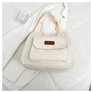 Dettaglio della borsa tote in tela bianco avorio con tasca frontale e etichetta in pelle