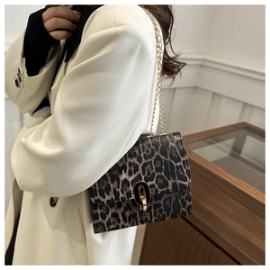 Detail of vintage leopard print crossbody bag featuring a golden chain strap and metal lock