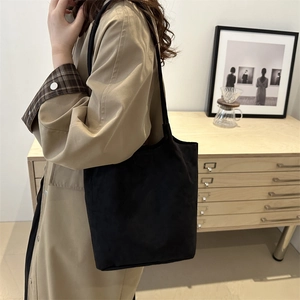 Minimalist black bucket tote bag styled with a khaki trench coat for a casual winter look