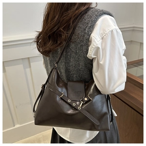 Detail of deep brown leather hobo bag with metal rivets and fashion text shown on model