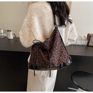 Détail du sac cabas léopard avec base en cuir noir et nœud décoratif sur le côté