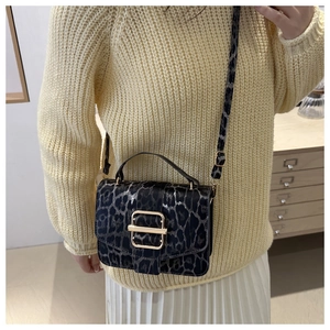 Gros plan du sac à bandoulière léopard avec boucle dorée porté à l'épaule