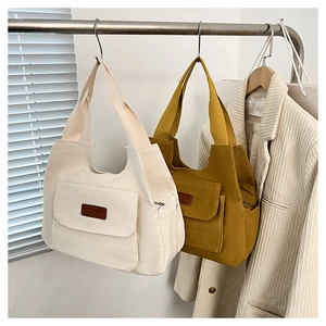 Dettaglio di borse tote in tela con toppa in pelle 'FASHION' e tasca con patta in beige e giallo