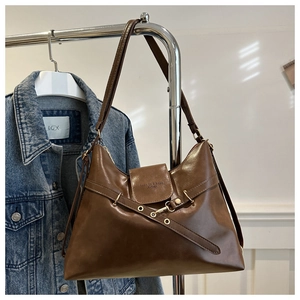 Detail view of brown vintage leather tote bag with gold hardware and embossed fashion logo