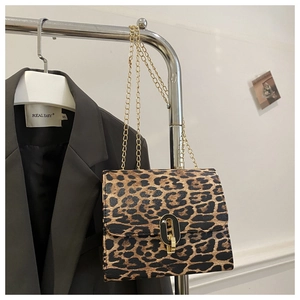 Detail of leopard print square bag featuring a gold chain strap and metal lock closure