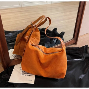 Detail of orange suede tote bag with adjustable strap and zipper on mirror reflection