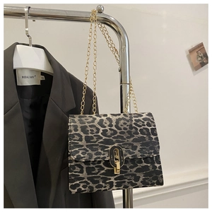 Detail of leopard print crossbody bag with gold chain strap on a blazer background
