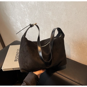 Close-up of matte black suede shoulder bag with silver zipper and leather strap