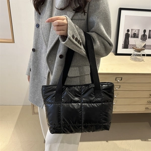 Sac fourre-tout matelassé noir en nylon brillant porté par un mannequin en studio